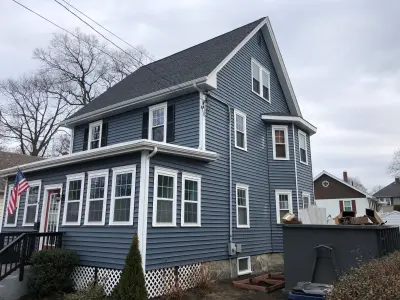 Tall gable end in blue with attic vent above fieldstone foundation