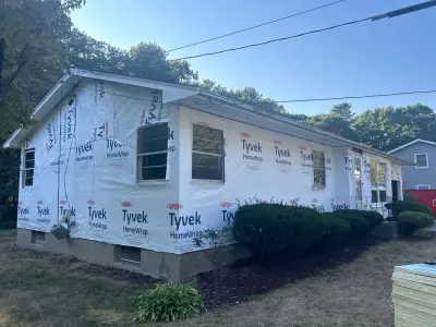 Light gray lap siding with white trim and new picture window on a Massachusetts ranch home - photo 35