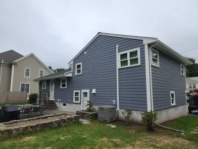 Blue-gray composite lap siding with white trim on a split-level home in Needham, MA - photo 4