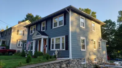 Light blue vinyl siding with white trim and black shutters on a home in Norwood, MA - photo 21