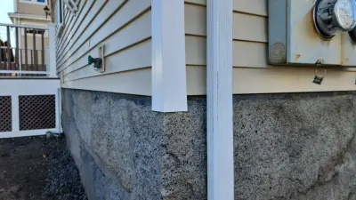 Street view of the two-family with new siding, white trim and original porch railings