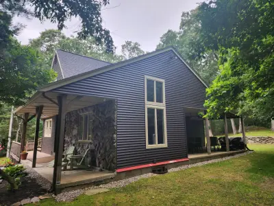 Rear elevation with fieldstone chimney, red flue pipe and covered patio