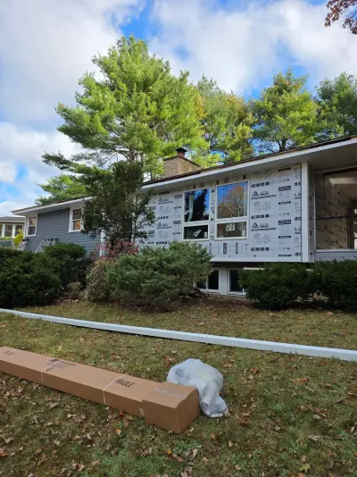 Foam-wrapped garage-end wall with new windows set and trim stock staged