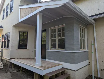 Tongue-and-groove porch floor on new framing with white boxed fascia and column base